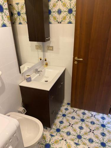 een badkamer met een wastafel, een toilet en een spiegel bij Casa stile mediterraneo Piazza Durante a Letojanni Taormina in Letojanni