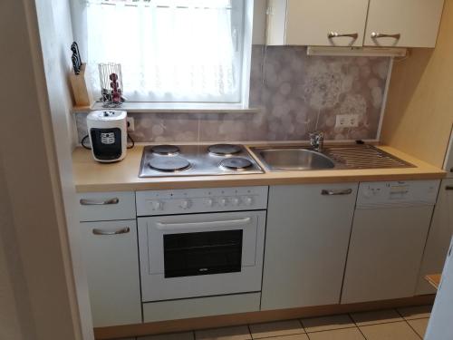 a small kitchen with a stove and a sink at Ferienwohnungen Vidoni in Bodensdorf