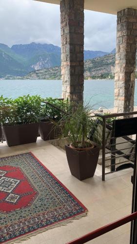 a patio with a table and potted plants next to the water at Hotel Paradiso Conca d'Oro in Nago-Torbole