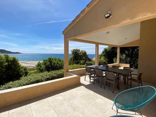 un patio avec une table et des chaises et l'océan dans l'établissement Maison de vacances avec vue imprenable sur la mer, à Calcatoggio