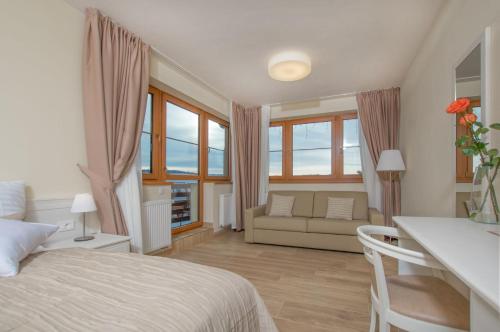a bedroom with a bed and a couch and windows at Hotel SLUNEČNÁ LOUKA in Lipno nad Vltavou