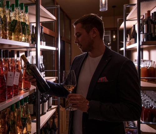 a man is standing at a bar holding a glass of wine at Hotel SLUNEČNÁ LOUKA in Lipno nad Vltavou