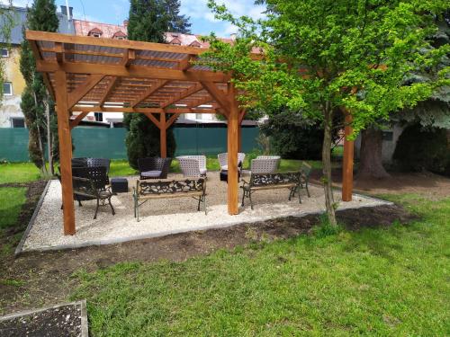 a wooden gazebo with benches and a tree at Bluestars Home in Karlovy Vary