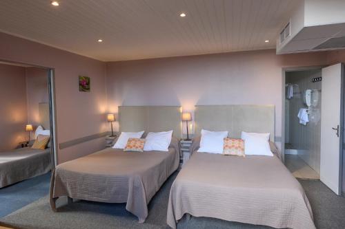 ジョワイユーズにあるHotel de l'Europeのベッド2台と鏡が備わるホテルルームです。