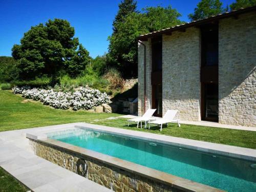 een zwembad in een tuin met twee stoelen en een huis bij Molino dei Ciliegi Splendida villa in Umbria in San Venanzo