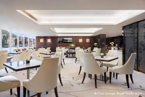 a restaurant with tables and white chairs at The Royal Pacific Hotel & Towers in Hong Kong