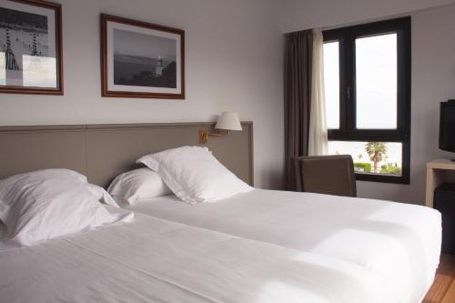
a white bed sitting in a bedroom next to a window at Hotel Ezeiza in San Sebastián
