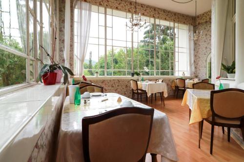 a restaurant with tables and chairs and large windows at Kurvilla am Park in Bad Kissingen