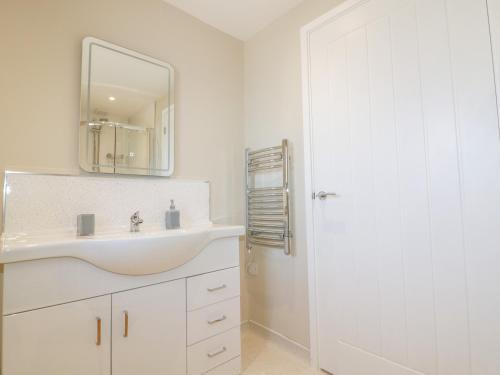 W białej łazience znajduje się umywalka i lustro. w obiekcie The Cornstore w mieście Bodmin