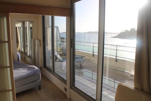 a room with a balcony with a view of the ocean at Résidence Le Crystal Dinard Plage in Dinard