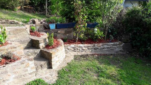 a garden with a stone wall and some plants at Eifel Duitsland fraai vakantiehuis met tuin in Eisenschmitt