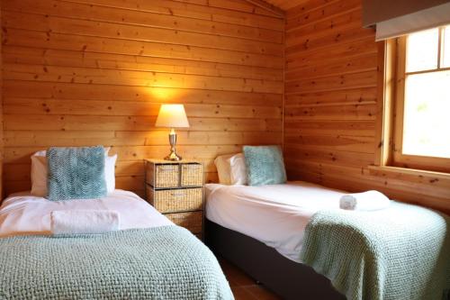 2 camas en una habitación con paredes de madera en Lodge 37 Rowardennan, Loch Lomond, en Glasgow