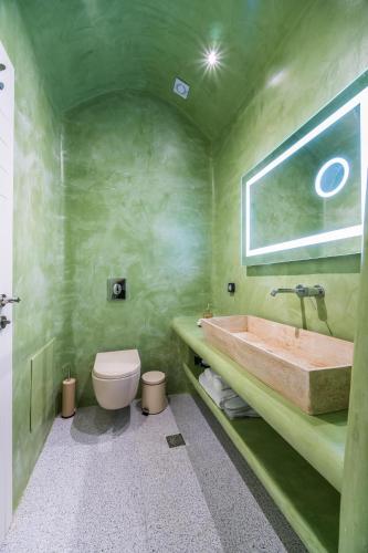 a green bathroom with a tub and a toilet at Aegean Blue Suites in Pirgos