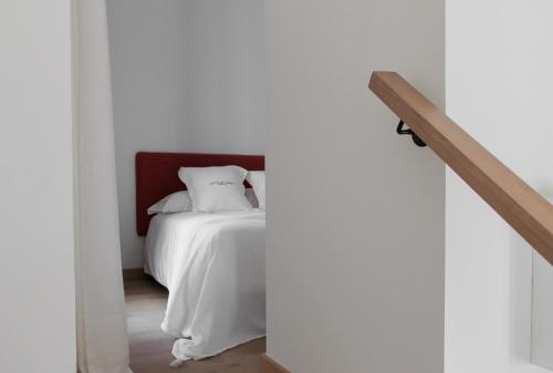 Un dormitorio con una cama blanca y una escalera en La Ermita Suites - Único Hotel Monumento de Córdoba, en Córdoba