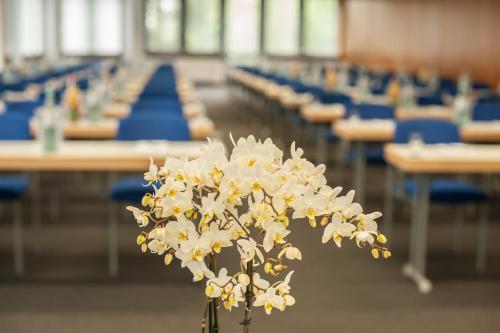 a vase filled with white flowers in a classroom at Atrium im Park Hotel Regensburg in Regensburg