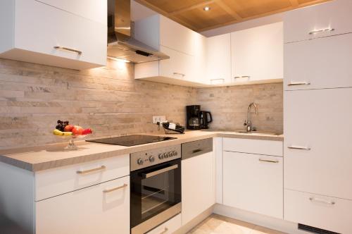 a white kitchen with white cabinets and a sink at Tyroler Hof in Grän