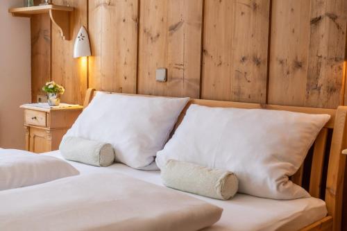 a bed with white pillows and a wooden wall at Bruggenwirt in Bruggen
