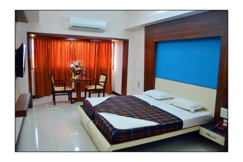 a bedroom with a bed and a table with chairs at Kediyoor Hotels in Udupi