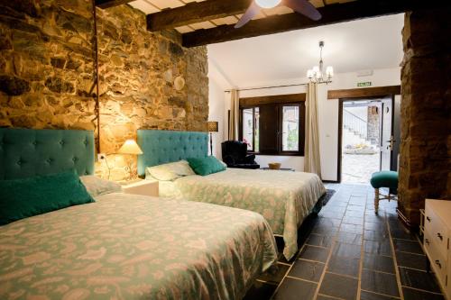 a bedroom with two beds and a stone wall at La Casa Grande Del Valle in El Valle