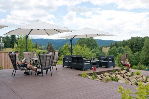 a woman sitting on a patio under two umbrellas at Pensjonat pod Samowarem in Tylicz