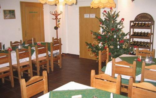 une salle à manger avec un arbre de Noël, des tables et des chaises dans l'établissement Pension Fontana, à Špindlerův Mlýn