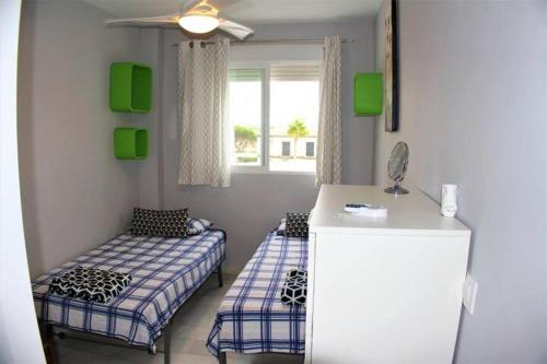 een kamer met 2 bedden, een bureau en een raam bij RETAMA GOLF Novo Sancti Petri in Chiclana de la Frontera