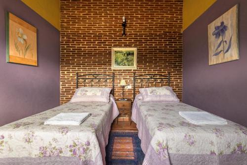 2 camas en una habitación con una pared de ladrillo en Casa Rural Laura, en Miranda del Castañar