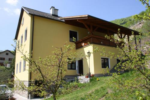 una casa amarilla en una colina con en Ferienwohnung Helga Bergkirchner, en Schwallenbach