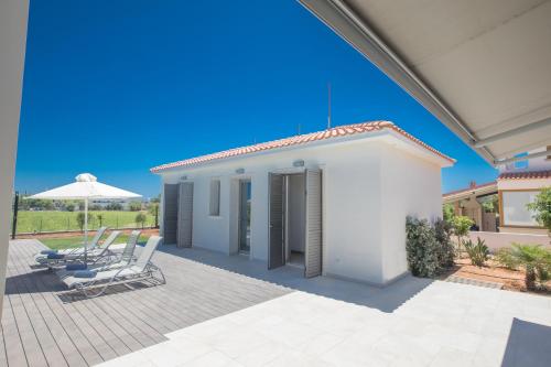 una casa bianca con due sedie e un ombrellone di Leda Villa a Protaras
