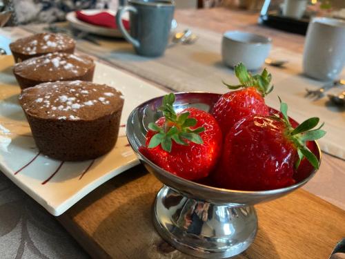 un piatto con una ciotola di fragole e dei cupcakes di La Ferme Buissonnière a Bardou
