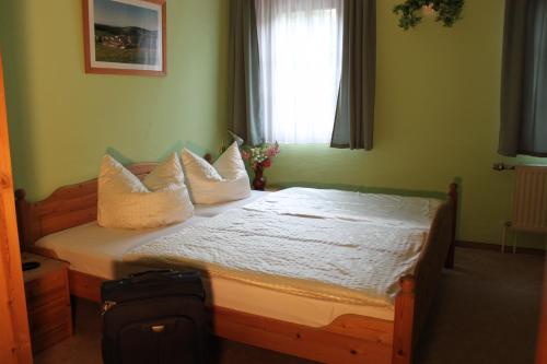 a bedroom with a bed with pillows and a window at Gasthof Hertigswalde in Sebnitz