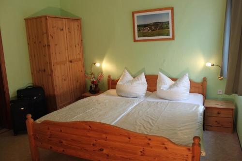 a bedroom with a large wooden bed with white pillows at Gasthof Hertigswalde in Sebnitz