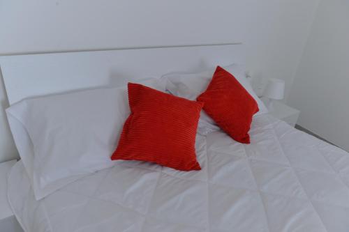 a white bed with two red pillows on it at Casa CarMa in Porto Ceresio