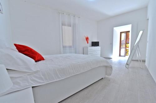 a white bedroom with a large white bed with red pillows at Casa CarMa in Porto Ceresio