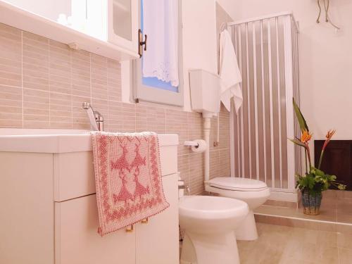 La salle de bains blanche est pourvue de toilettes et d'un lavabo. dans l'établissement Monte Astili, à Lanusei