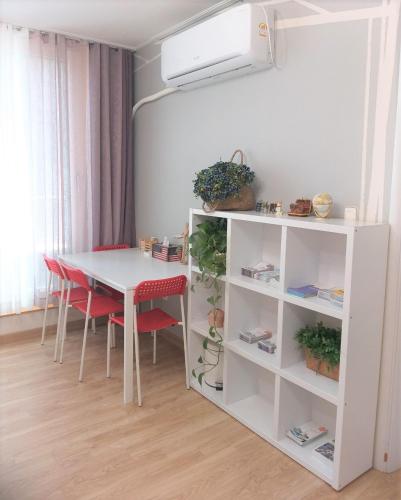 a white table with red chairs and a white shelf at Mr. Kim Guesthouse in Incheon