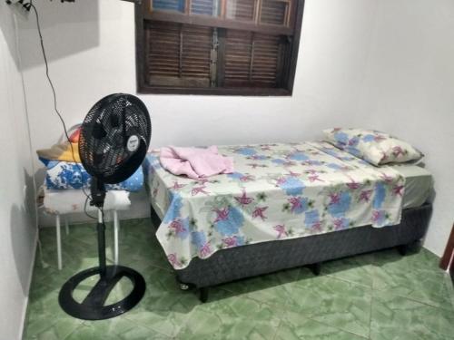 a small bedroom with a bed and a fan at Chalé saí azul in Penedo