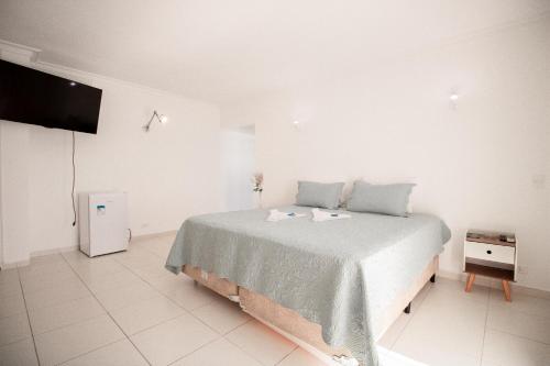 a white bedroom with a bed and a flat screen tv at Pousada Refúgio das Estrelas - Vista para o Mar in Ilhabela