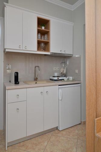 a kitchen with white cabinets and a sink at Epavlis Luxury apts in Leptokaria