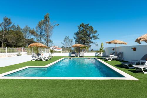a swimming pool in a yard with chairs and umbrellas at Quinta Bogesi in Figueira da Foz