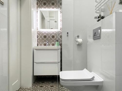 a white bathroom with a toilet and a mirror at Beautiful studio for couples - Old Town & Main station in Krakow
