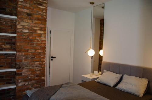 ギジツコにあるnautica lux apartamentyのレンガの壁のベッドルーム(ベッド1台、鏡付)