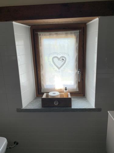 a bathroom with a window with a heart drawn on the curtain at Ca di Nadia in Aosta