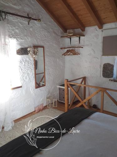 a bedroom with a bed and a mirror on the wall at Ninho Bico-de-Lacre ~ o paraíso é a/na Terra in Balocas