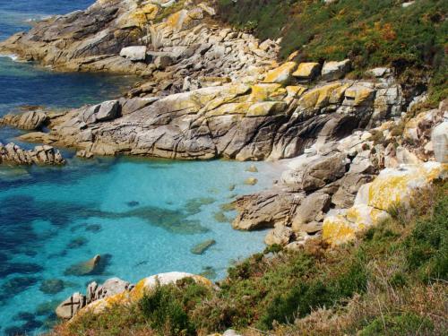 a large pool of blue water on a rocky coast at Innmare Fortuna Hotel Dos Estrellas in Marín