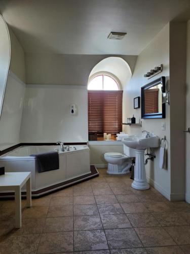 a bathroom with a tub and a toilet and a sink at Orange Bistro in Baie-Saint-Paul