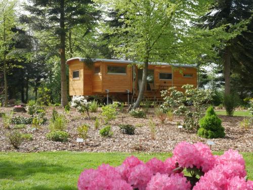 a tiny house in a garden with pink flowers at Tiny House, Kleinod im Grünen in Emstek