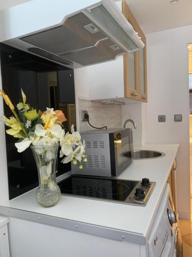 a vase of flowers sitting on a counter in a kitchen at Joli studio tout confort avec toutes commodités in Vaulx-en-Velin