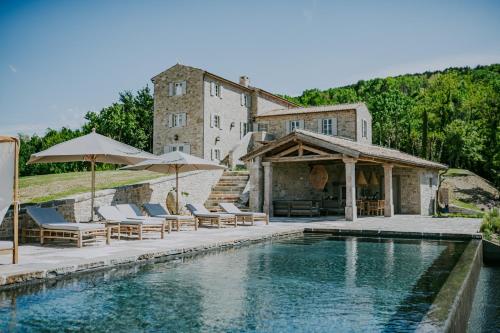 einem Pool mit Stühlen und Sonnenschirmen vor einem Gebäude in der Unterkunft Luxury estate with 6 hectares land near hilltop town Motovun in Kaldir