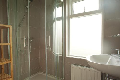 a bathroom with a glass shower and a sink at Vakantiewoning K&W NOT FOR COMPANIES in Ouddorp